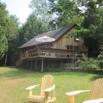 View of house and lawn with Adirondack chairs